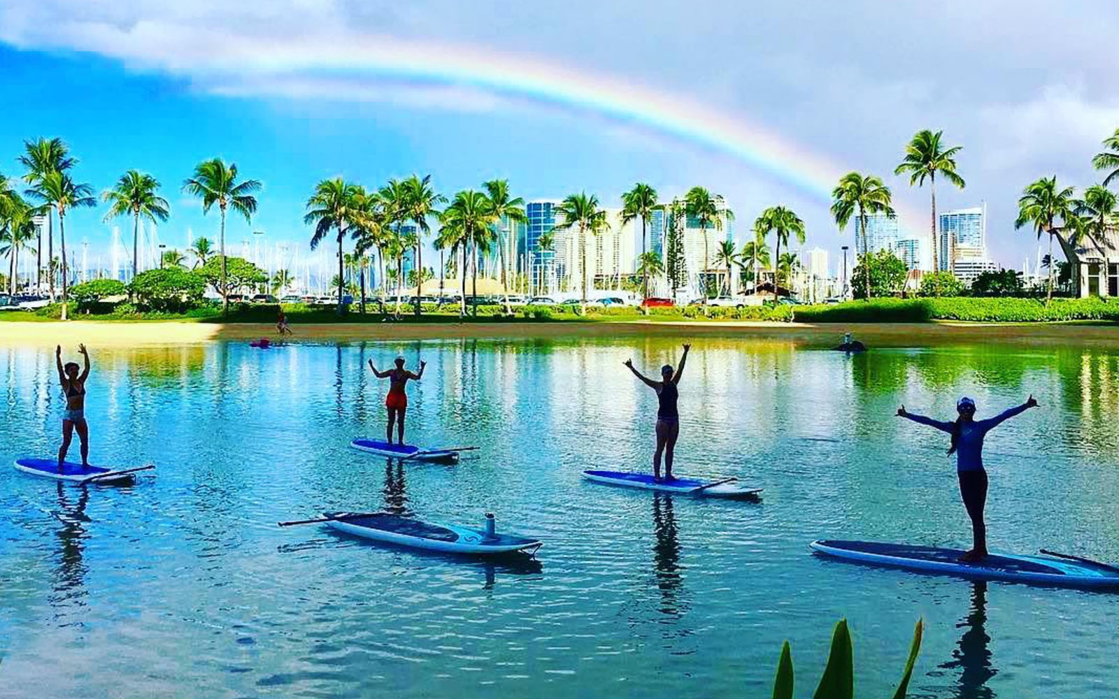 Stand up paddle yoga with rainbow in Waikiki lagoon